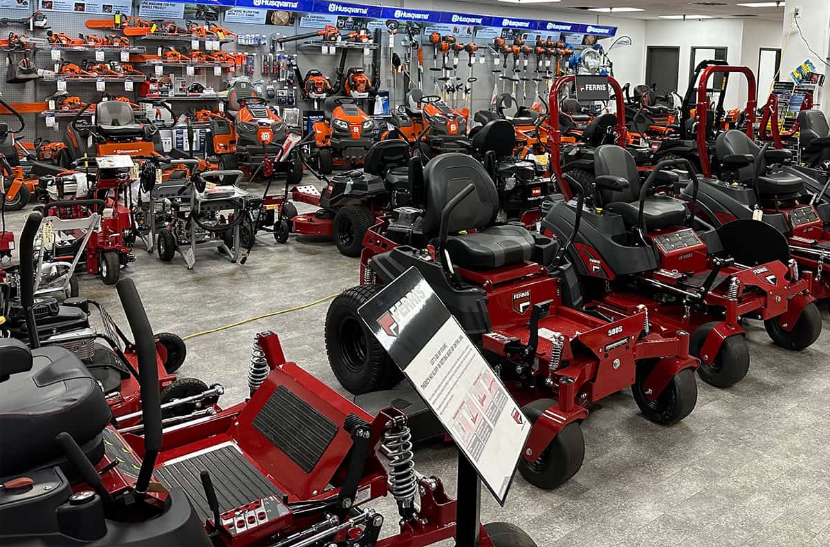 Heinold & Feller | Many lawn mowers are on display in a store.